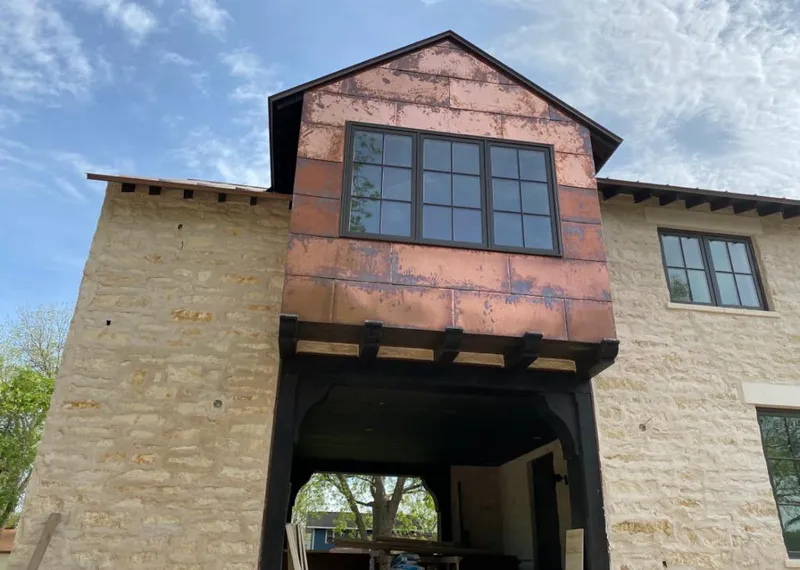 Copper metal panel facade on a stone building for Roof Repair in Phelan