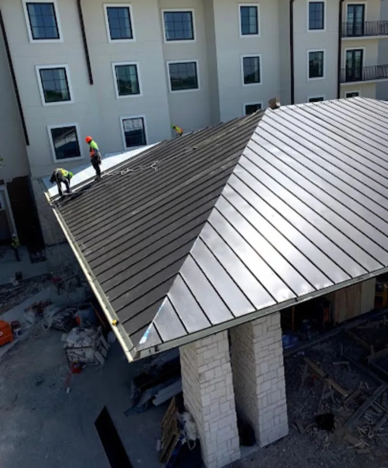 Crew installing standing seam metal roof panels on a commercial project in Phelan